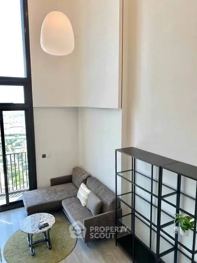 Modern living room with high ceiling and large window offering city views.