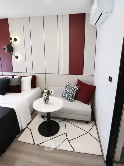 Modern bedroom with stylish decor and cozy seating area, featuring elegant lighting and contemporary design.