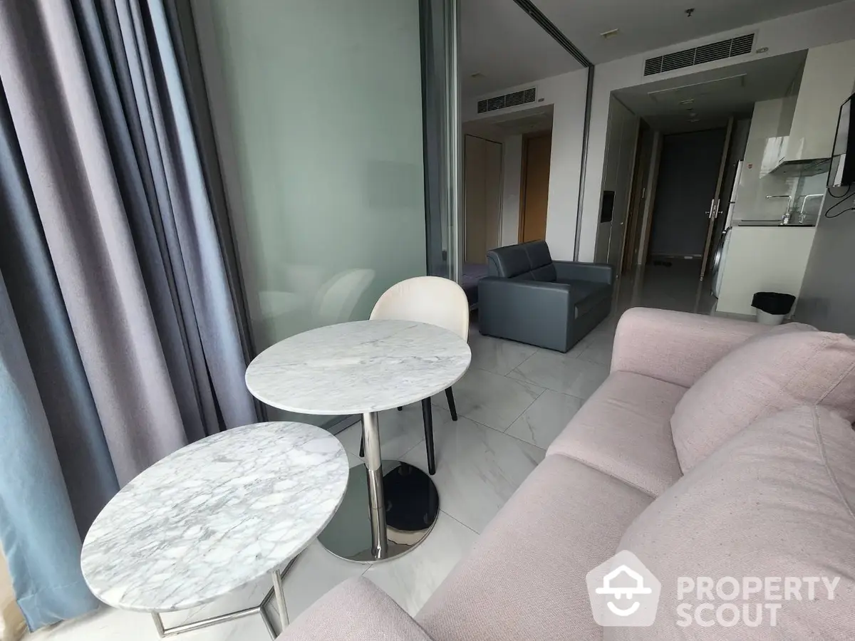 Elegant living room with plush pink sofa and marble-top tables, modern design with ample natural light and sophisticated decor for a luxurious lifestyle.