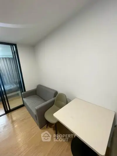Cozy modern living area with sofa, chair, and table in a compact apartment setting.