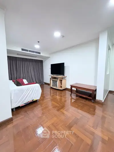 Spacious living room with wooden flooring and modern furnishings in a stylish apartment.