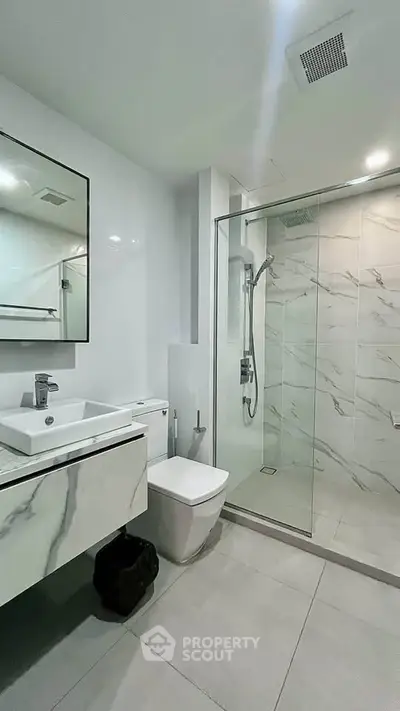 Modern bathroom with sleek design, featuring a glass shower enclosure and stylish vanity.