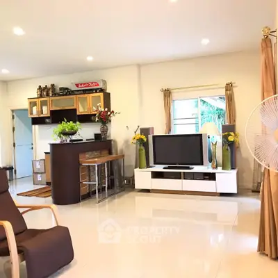 Spacious living room with modern decor and natural light, featuring a sleek entertainment center and elegant furnishings.