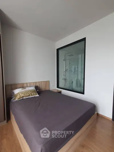 Modern bedroom with glass-enclosed shower and wooden flooring