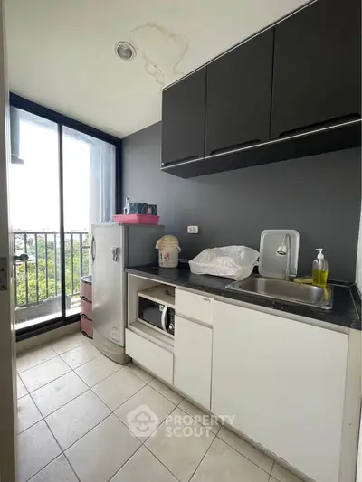 Modern compact kitchen with balcony view, featuring sleek cabinetry and essential appliances.