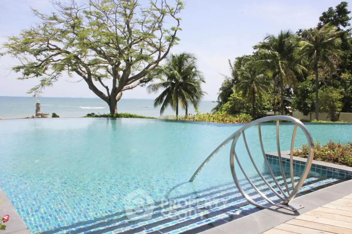 Stunning beachfront infinity pool with ocean view and lush tropical surroundings.
