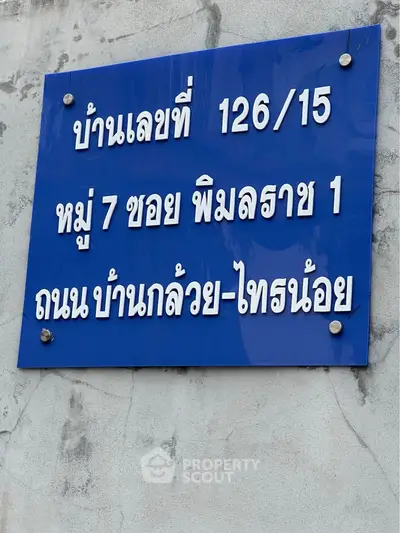 Blue real estate sign with address details in Thai language.