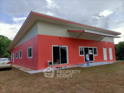 Modern red single-story house with large windows and a sloped roof.
