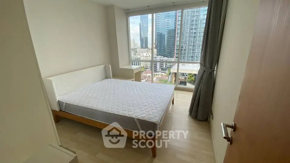 Modern bedroom with large window and city view in high-rise apartment