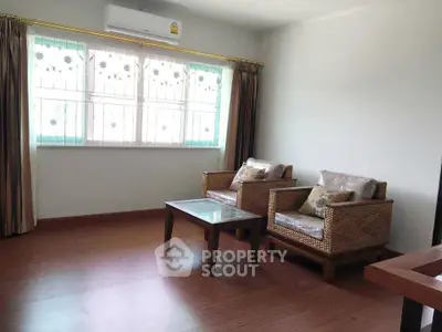 Cozy living room with wicker chairs and natural light through large window.