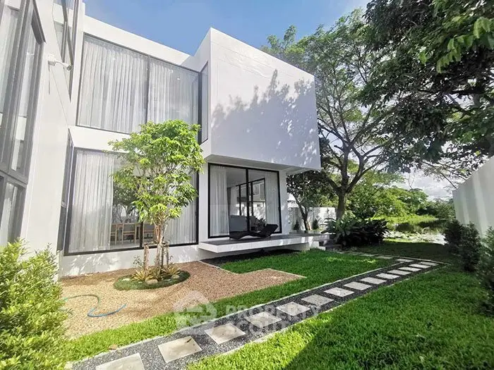 Modern white house exterior with lush green garden and large windows