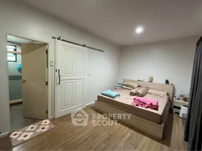 Spacious bedroom with modern decor and ensuite bathroom, featuring wooden flooring and cozy lighting.