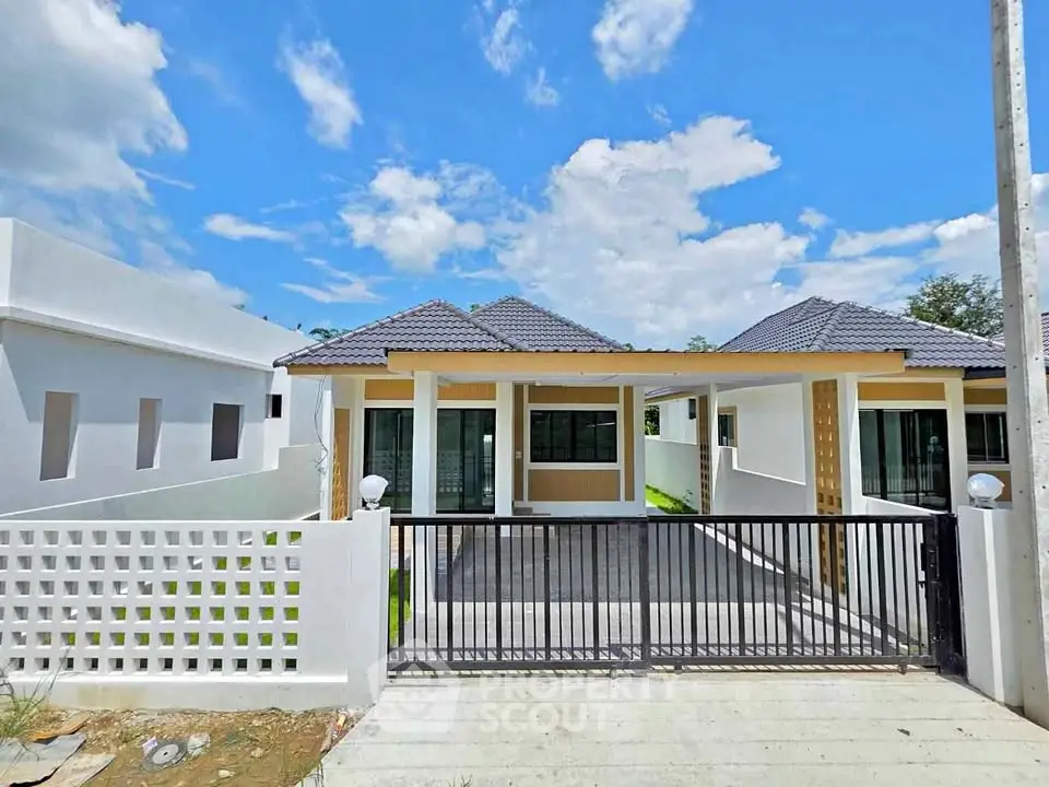 Modern single-story house with gated entrance and spacious driveway under a clear blue sky.