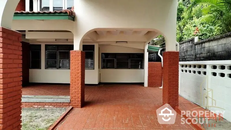 Charming single-story home with terracotta tiles and arched carport, offering a spacious outdoor area and lush greenery in a serene neighborhood.