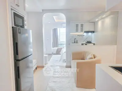 Modern open-plan living area with sleek kitchen and cozy seating, featuring bright natural light.