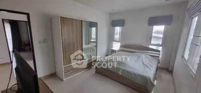 Spacious bedroom with modern wooden furniture and large windows for natural light.