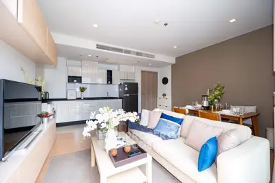 Modern open-layout living room with stylish kitchen and dining area, featuring elegant decor and ample natural light.