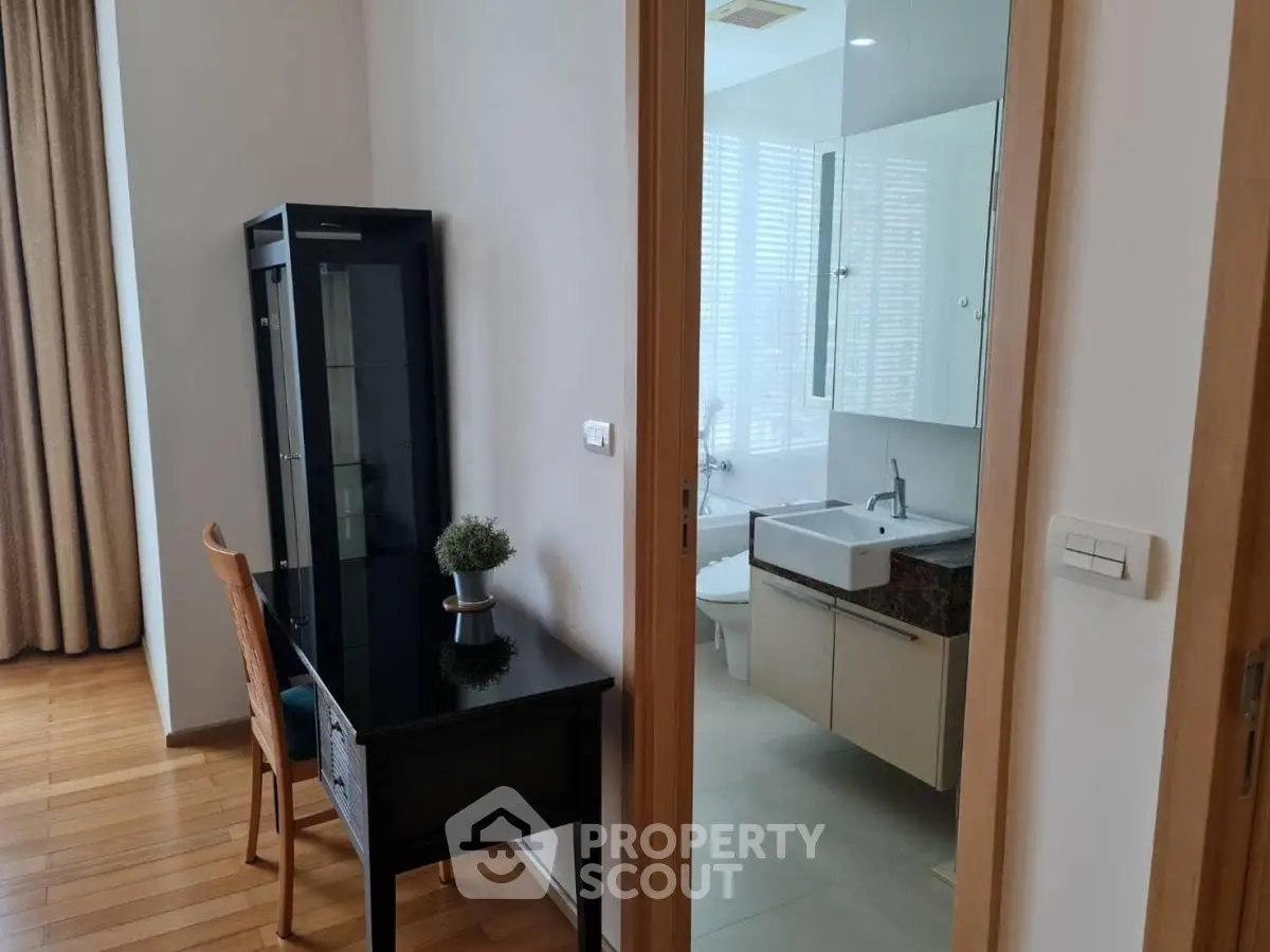 Modern apartment with study area and bathroom, featuring sleek design and natural light.