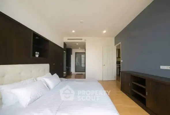 Spacious modern bedroom with elegant wooden furnishings and natural light.