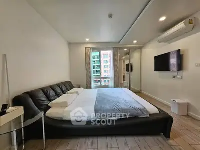 Modern bedroom with sleek design, featuring a large bed, wall-mounted TV, and air conditioning.