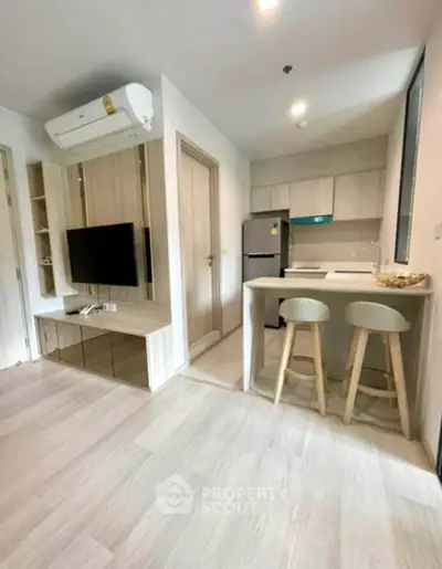 Modern open-layout living room with sleek kitchen and stylish bar stools in a cozy apartment.
