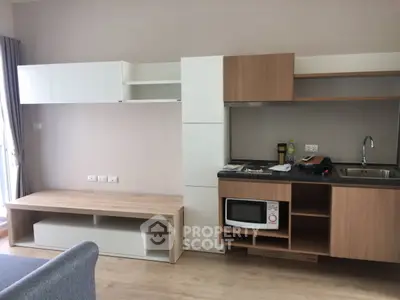 Modern kitchen with sleek cabinetry and built-in microwave in a stylish apartment.