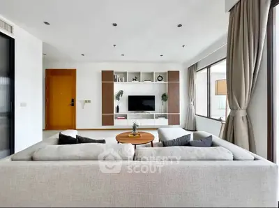 Spacious modern living room with large windows and stylish furniture.