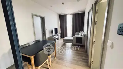 Modern living room with dining area, featuring sleek furniture and natural light.