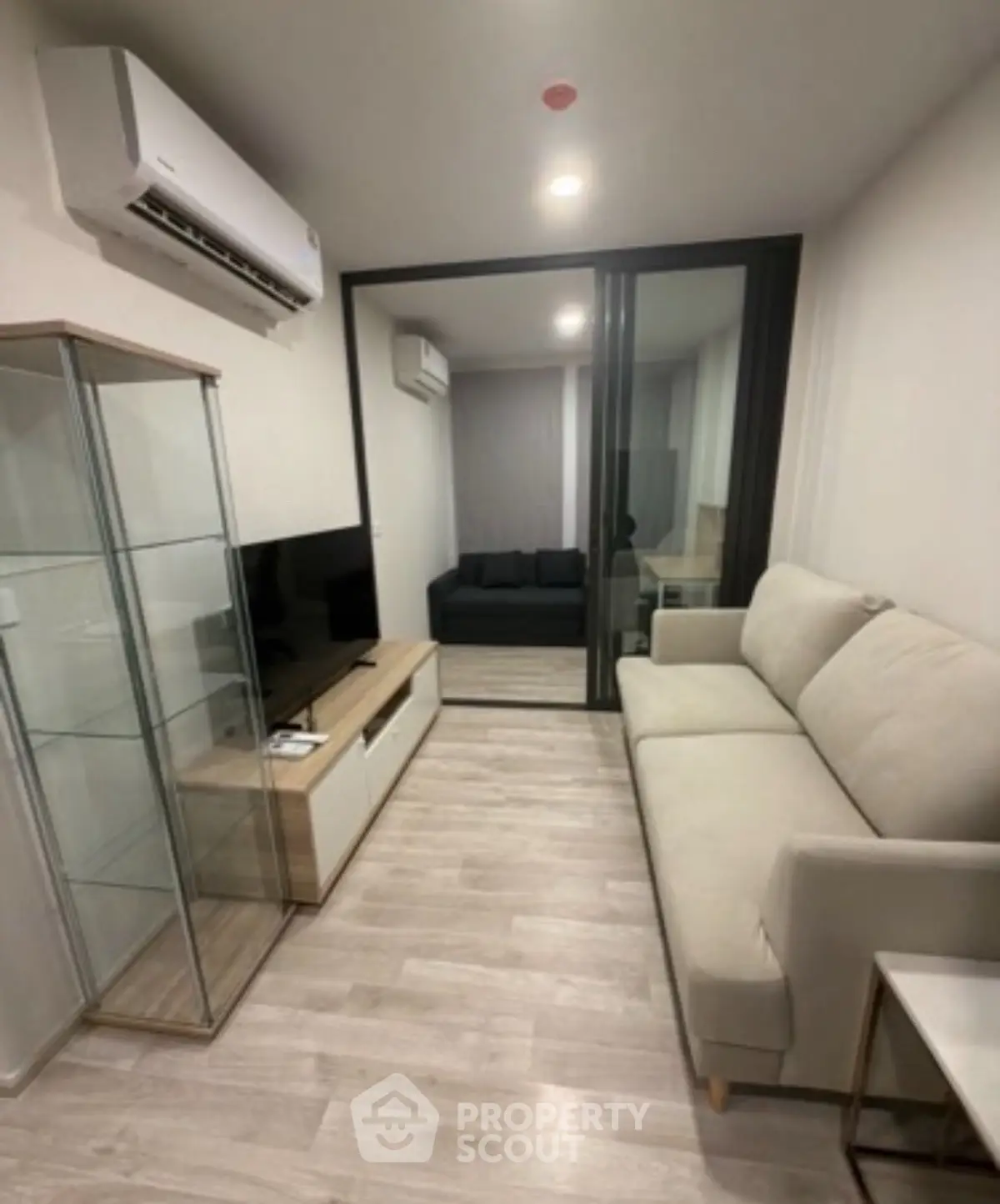 Modern living room with sleek glass cabinet and cozy sofa in a stylish apartment.