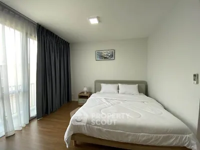 Spacious bedroom with modern decor and large window for natural light