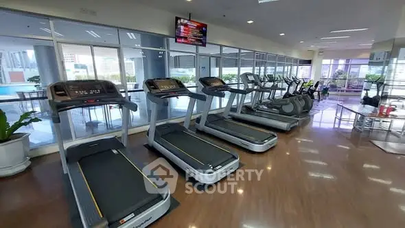 Modern gym with treadmills and city view, perfect for fitness enthusiasts.