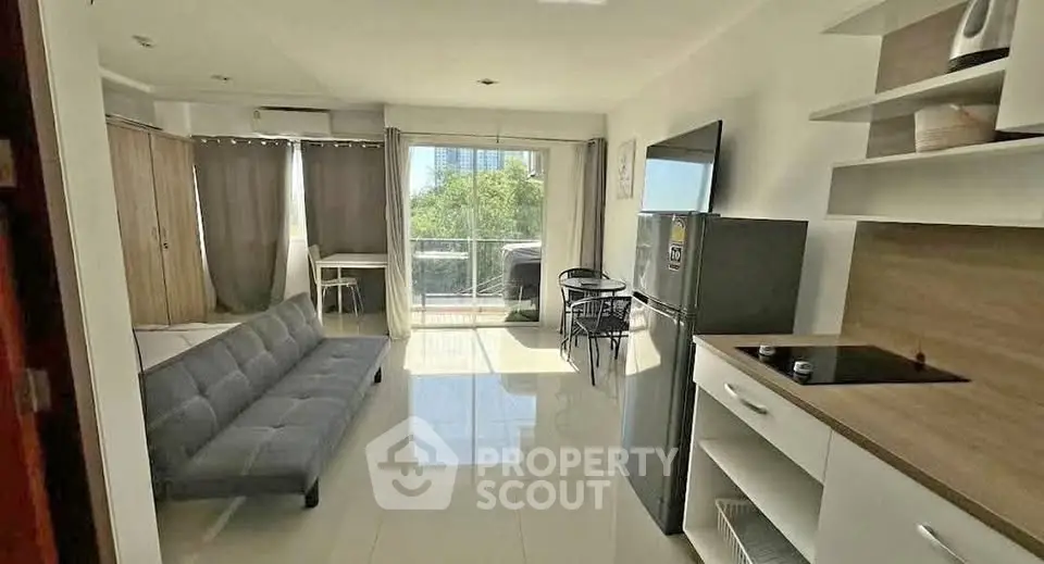 Modern open-plan living room with sleek kitchen and balcony view, featuring contemporary furnishings and natural light.