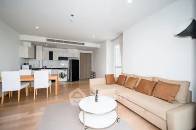 Modern open-plan living room with kitchen, featuring a cozy beige sofa and dining area.