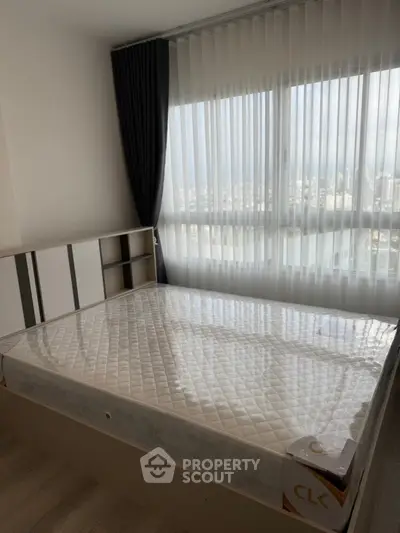 Modern bedroom with large window offering city view and natural light.