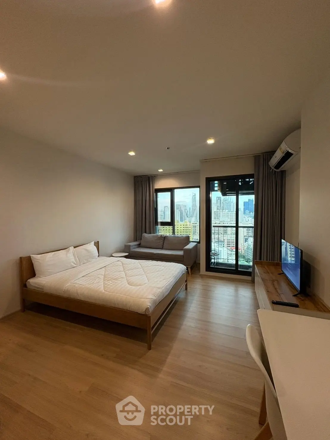 Spacious bedroom with city view, featuring modern furnishings and natural light.