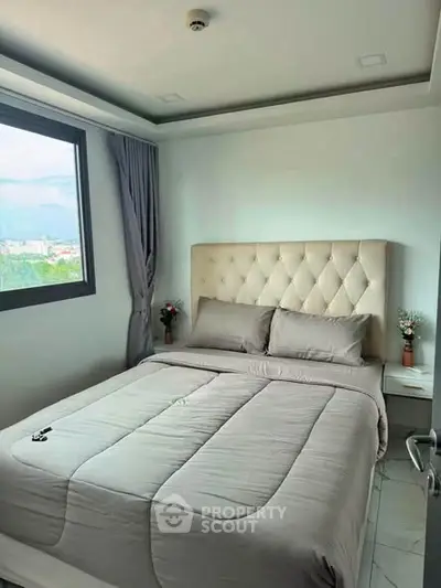 Cozy bedroom with plush bed and large window offering scenic views, perfect for relaxation and comfort.