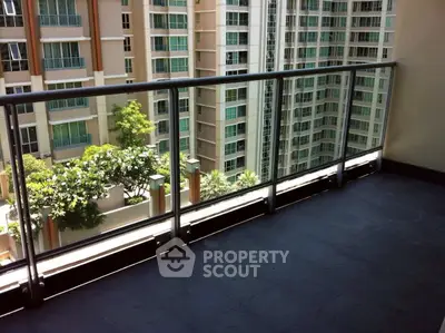 Spacious balcony with modern railing overlooking urban high-rise buildings.