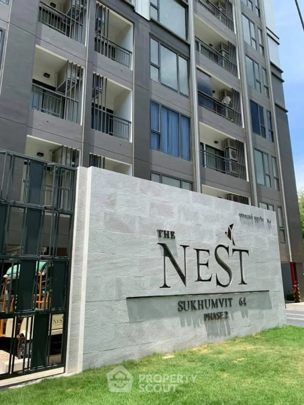 Modern condominium building exterior with The Nest Sukhumvit 64 signage, showcasing urban living.