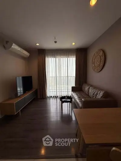 Modern living room with sleek furniture and large window offering natural light.