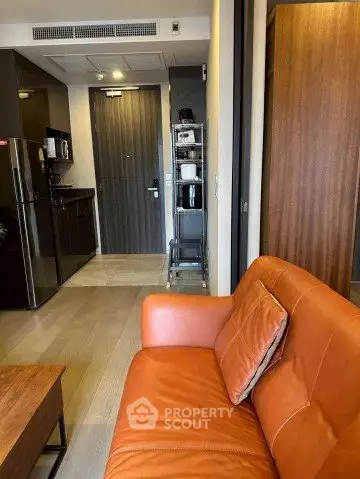 Modern apartment interior with stylish kitchen and cozy living area featuring a leather sofa.