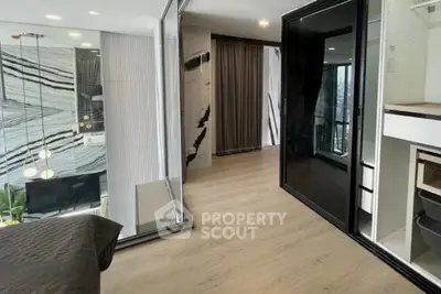 Modern bedroom with sleek design and large windows offering natural light and city views.