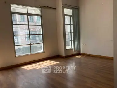 Spacious empty room with large windows and wooden flooring