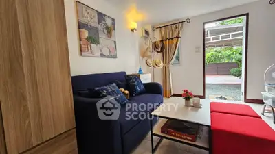 Charming living room with cozy blue sofa and vibrant red ottoman, perfect for relaxation and entertaining.