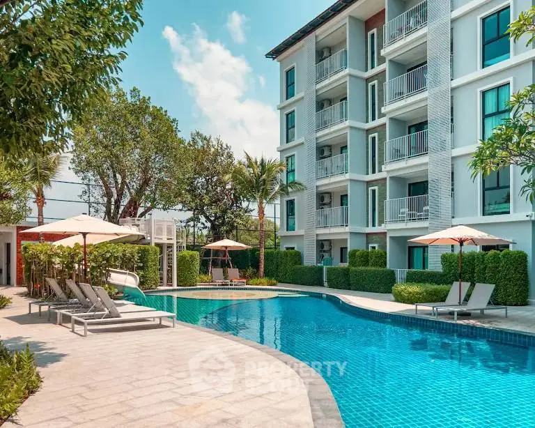 Luxurious apartment complex with a stunning outdoor pool and lush greenery.