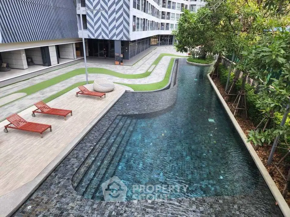Luxurious modern apartment complex with stylish pool and sun loungers, perfect for relaxation and leisure.