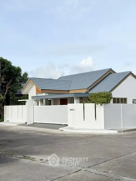 Charming modern house with white facade and blue roof in serene neighborhood.