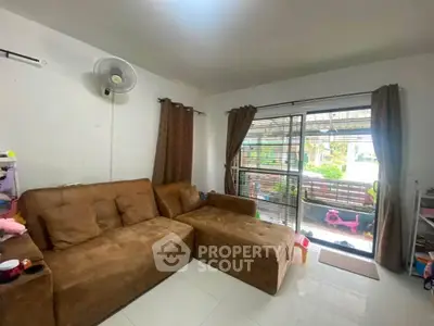 Cozy living room with brown sectional sofa and large window overlooking garden