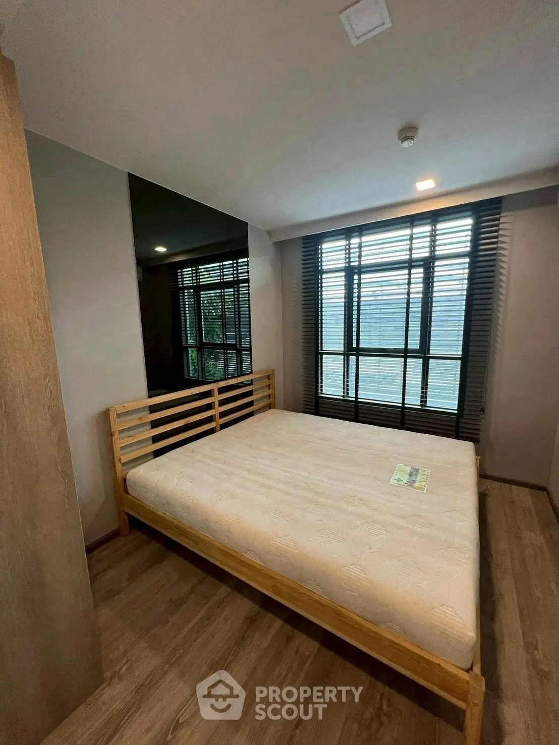Cozy bedroom with wooden bed frame and large window for natural light