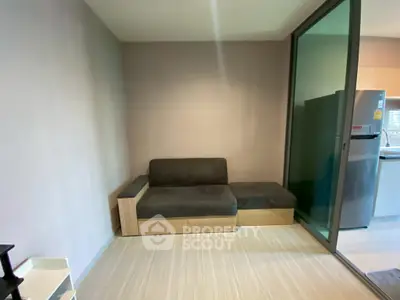 Modern living room with sleek sofa and glass partition leading to kitchen