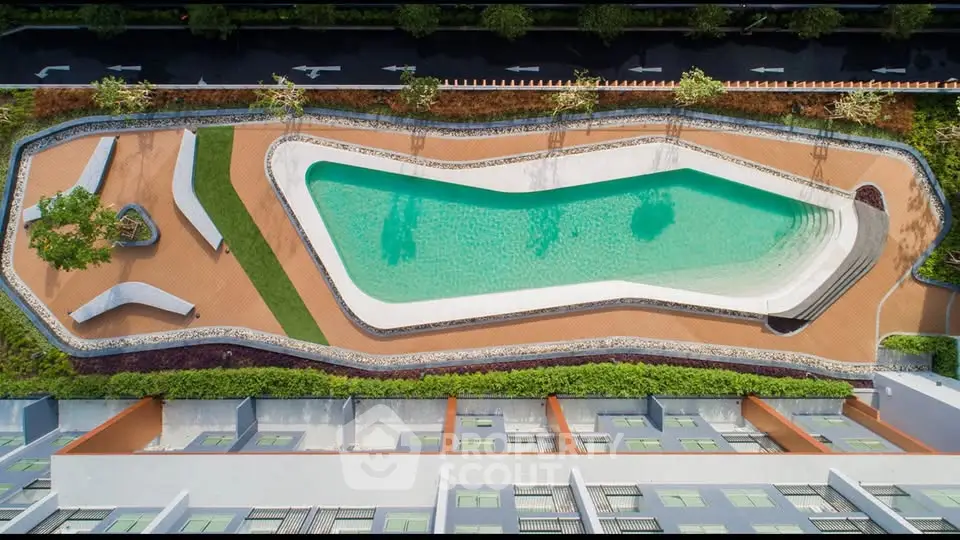 Stunning aerial view of modern residential complex with unique pool design and lush landscaping.